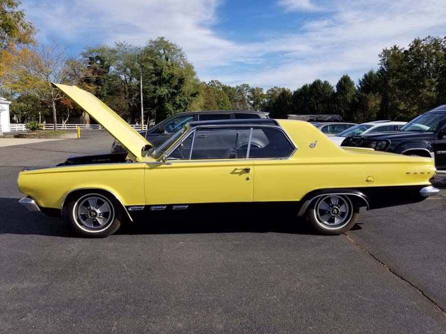 Yellow antique car with hood up in parking lot